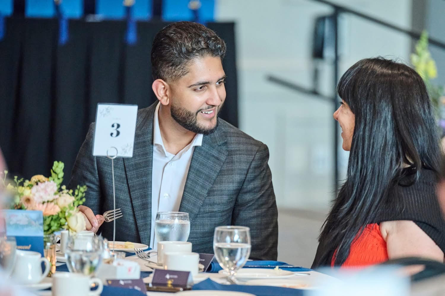 Arsh Kaler in conversation with a guest at a community dinner in Abbotsford